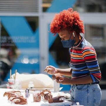 Art student paints multiple hands made out of plaster outside under the sun