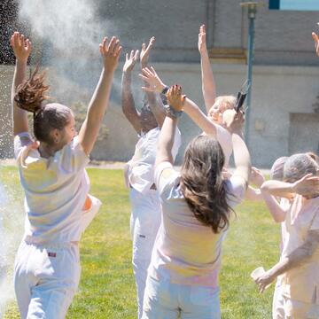 Group of nursing students throw colored powder in the air.