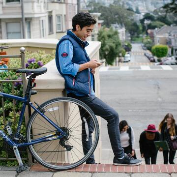 Student leans on wall next to bicycle