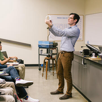 Professor demonstrating physics in front of class.