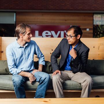 Two people sit on a bench and discuss