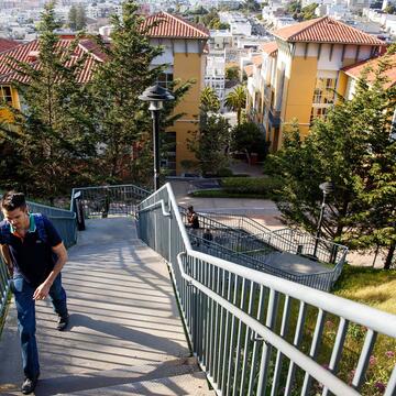Student walking up stairs with view of Loyola Village in the background