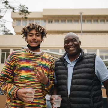 Student and parent pose in front of building