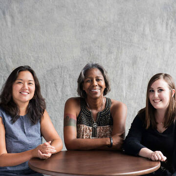 Three students sitting at a table smiling.