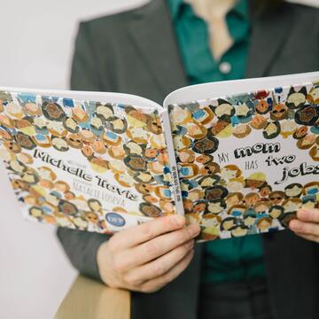 Person reading book titled My Mom has Two Jobs