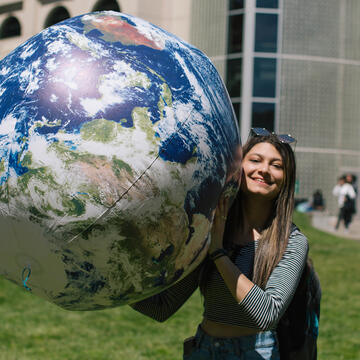 Student holding a large earth shaped ball