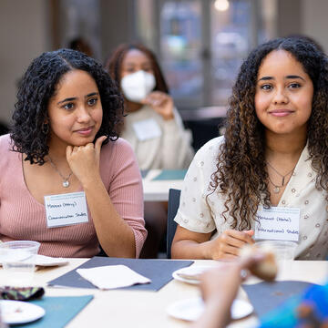 Students chat around a table while eating.