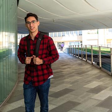 Student walking along the edge of a bulding on USF campus.