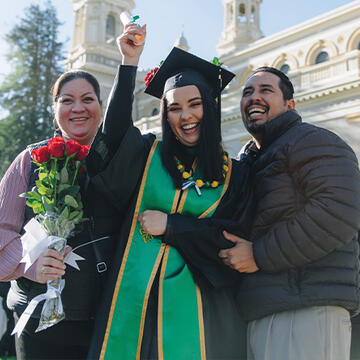 Student at graduation with loved ones in front of St. Ignatius