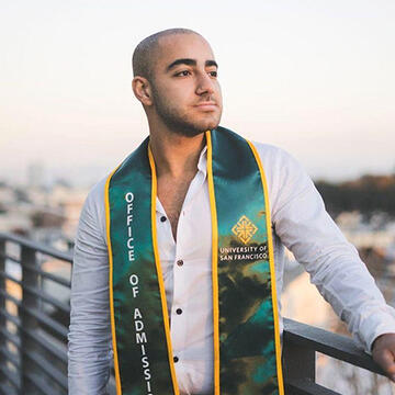 Jacob Sidaros looking to his left, wearing an Office of Admission stole