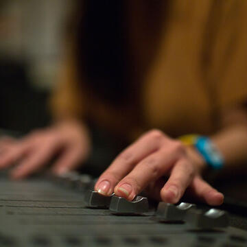 Student works the sliders on a mixing board.