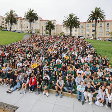 New Fall 2022 students sit for a group portrait on a grassy hill.