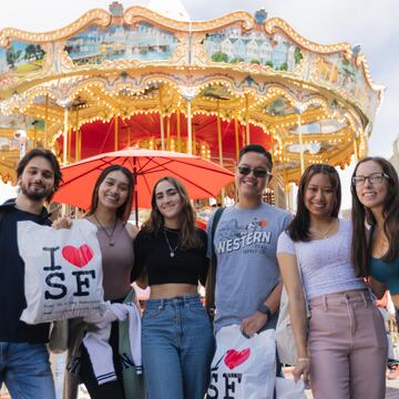 Six students standing in front of the Pier 39 carousel