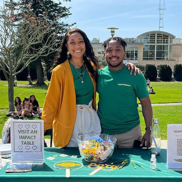 Two staffers at the involvement fair work at a resource table