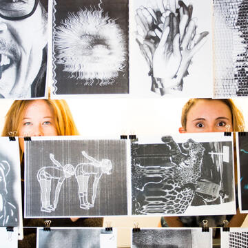 two students peeking through illustrations hanging on strings