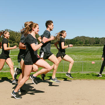 USF cross-country team running and passing by coach