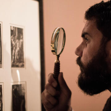 Person inspecting prints with a magnifying glass