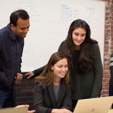 Students sitting at a table with their laptops.