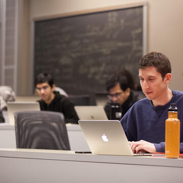 Students in a classroom looking at a laptop