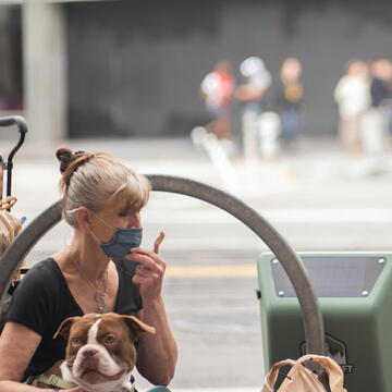 A homeless person and their dog with Zac Clark's solar power backpack