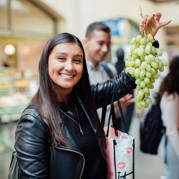 student holds up grapes in the Ferry Building