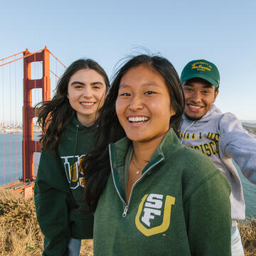 Students smile and pose in front of the Golden Gate Bridge.