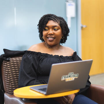 student smiles over laptop in class