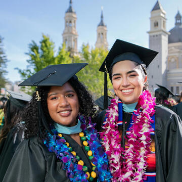 Two USF graduates posing in front of St. Ignatius