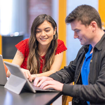 Two students study over a laptop.