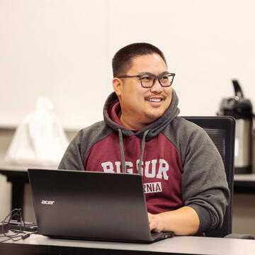 USF student with their laptop open smiling in class