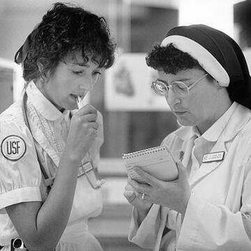 two nurses talking together holding notepad