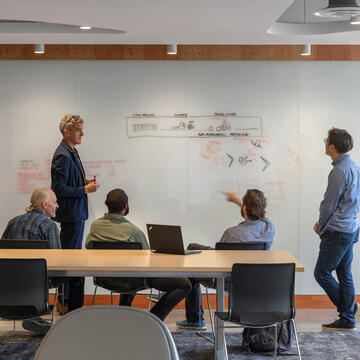 Five people collaborating in front of a white board.