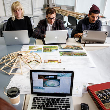 three students using their laptops in architecture class