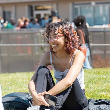 student sitting on grass and laughing