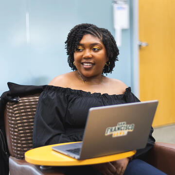 USF student smiling, sitting in front of laptop