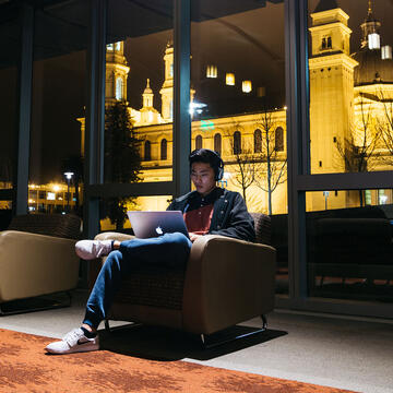 Student studies on laptop in a dark room.