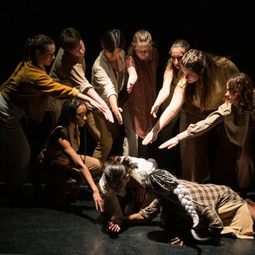 a group points at a couple on the ground during a dance performance