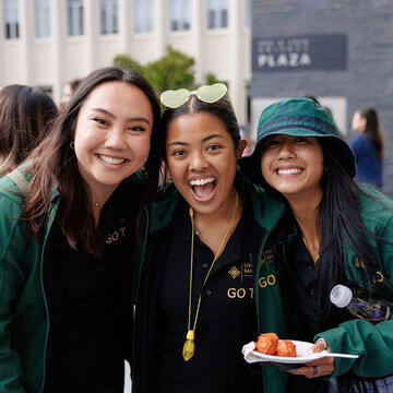 Three USF students smiling and posing together