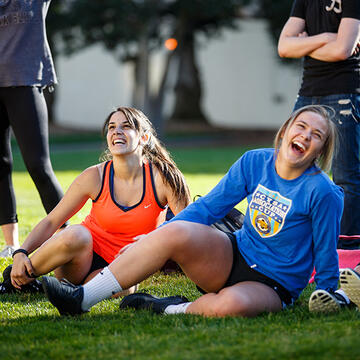 two girls sitting on grass stretching