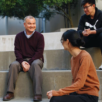 Fr. Joseph speaks to a group of students sitting on steps