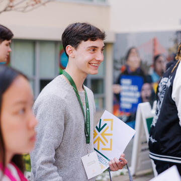student worker holds clipboard at event