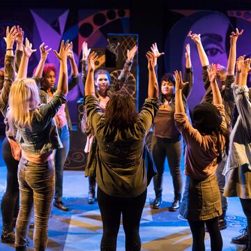 Students performing with their hands up