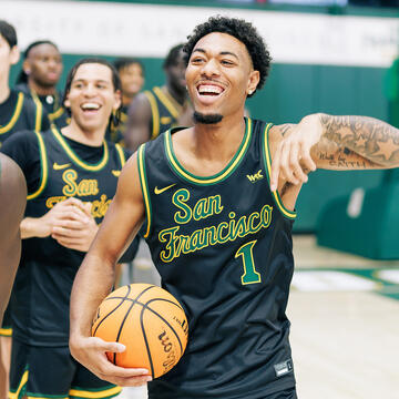 student cheerfully holds basketball