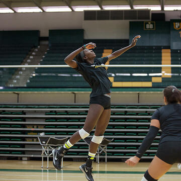 student jumps into air during volleyball tournament