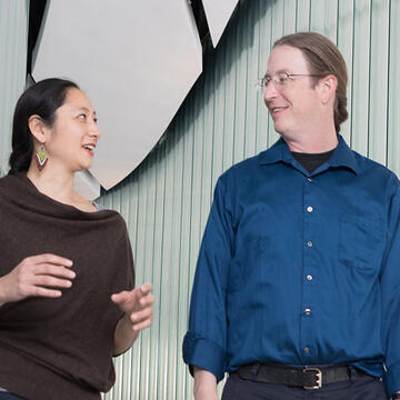 Two professors walk down a hallway talking to each other