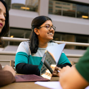 student sitting outside with her laptop smiling