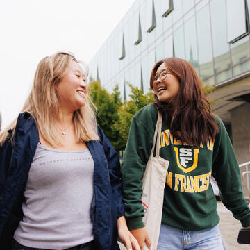 Two USF students walking and laughing on campus