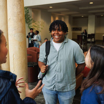 Three USF students chatting on campus, smiling