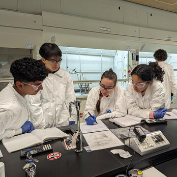 students in lab coats conduct experiments