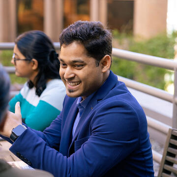 student sitting at a table outside smiling